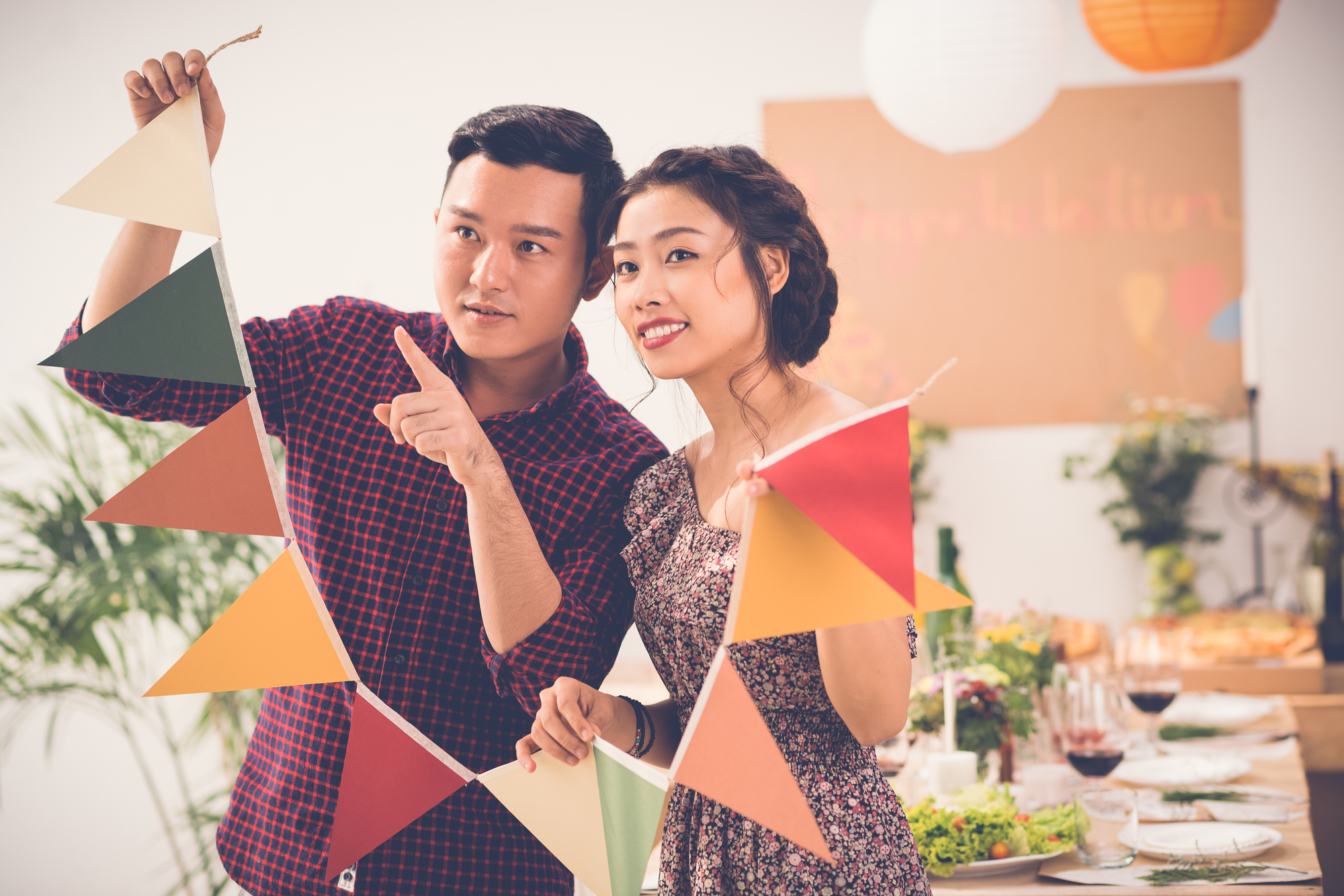 Vietnamese couple deciding where to put garland when preparing for party